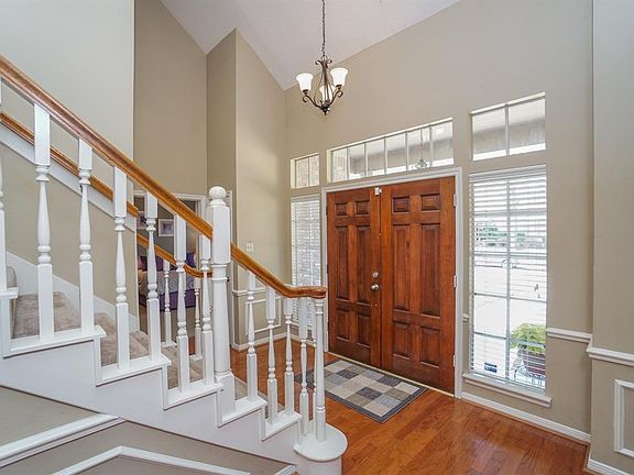 Entry hall features gorgeous floors, lighting feature, and staircase.