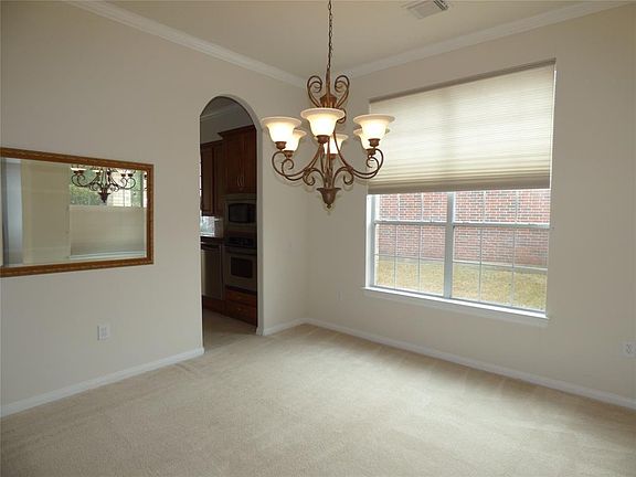 The formal dining room has crown molding, a decorative chandelier and windows overlooking the front porch and the side yard. A doorway opens to the kitchen for ease in serving your guests.