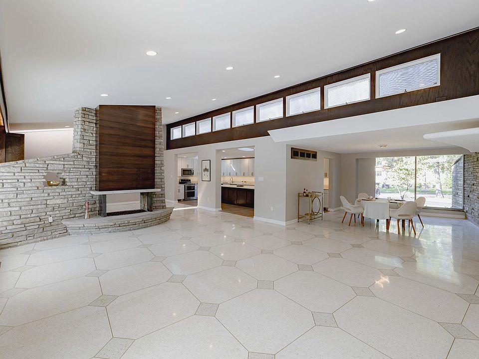 Living Room opens to dining room and kitchen. Vaulted ceilings. Undermount lighting. Re-Finished Terrazzo in classic pattern. Contemporary Walnut Fireplace Mantle. Stone Hearth. 2 sided gas fireplace.