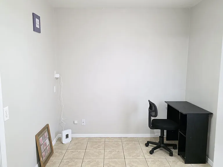Versatile flex space with tile flooring, neutral walls, and a dedicated desk area for work or study.