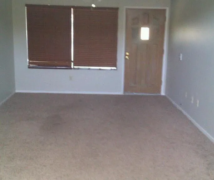 Living room of with front door and mountain views from front window and door. Photo taken from kitchen entrance.