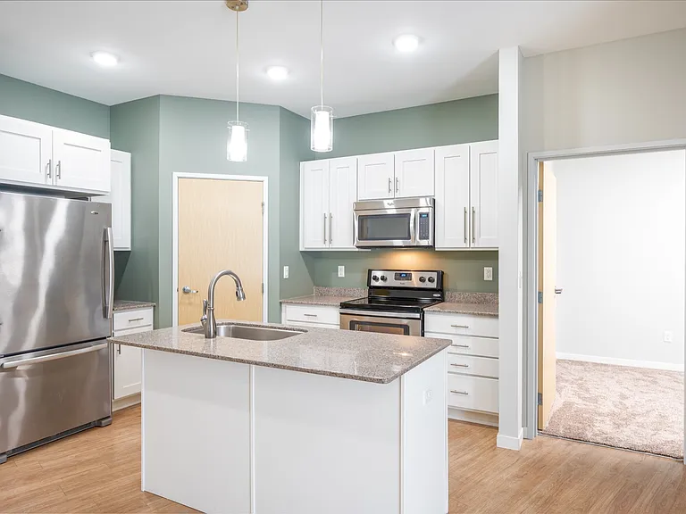 Contemporary kitchen with sleek stainless steel appliances, elegant granite countertops, white cabinets, and inviting hardwood floors. Contemporary kitchen with sleek stainless steel appliances, elegant granite countertops, white cabinets, and inviting ha