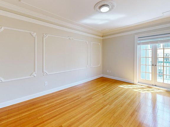 Spacious room with a wood-like flooring and a large window offering natural light