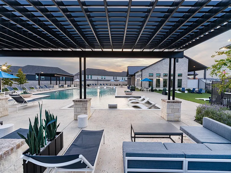 A covered poolside lounge at Amavi Celina with shaded seating, open views, and inviting spaces to relax or gather throughout the day.