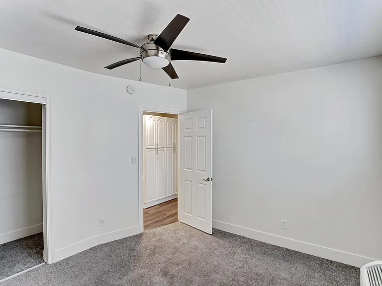 A room with a ceiling fan and a door.