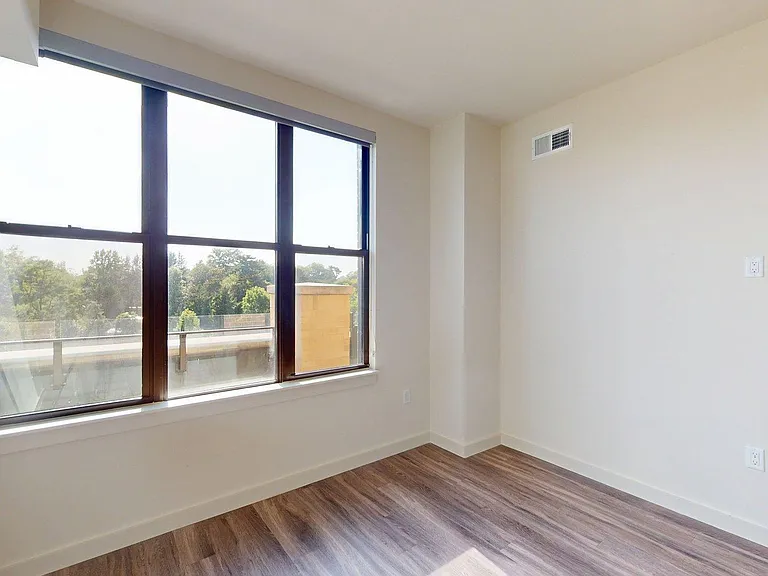 Spacious apartment bedroom with wood style floor.