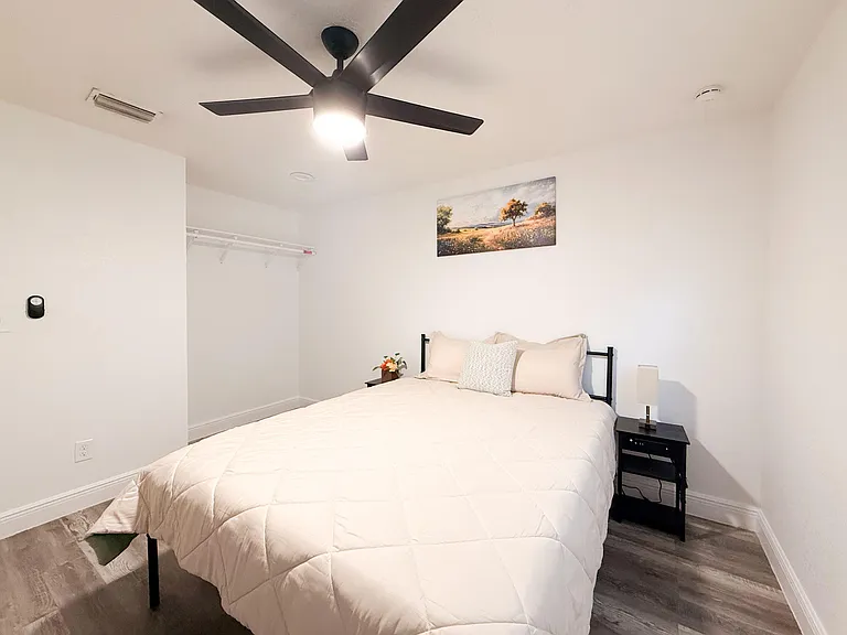 Private bedroom with a queen bed, ceiling fan, and convenient open closet shelving for everyday storage.