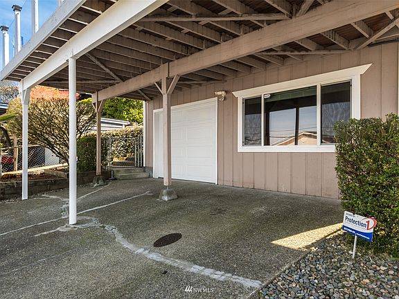 Driveway with one car garage and covered parking area.