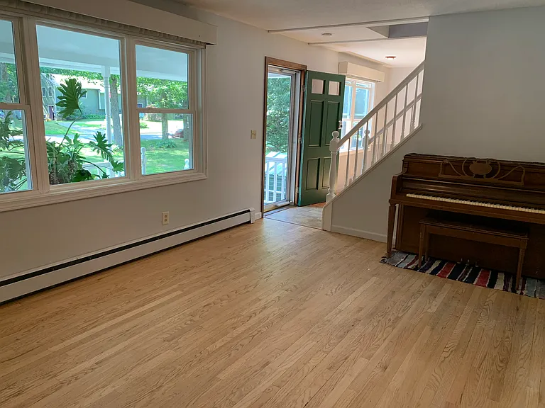 Front living room with gas fireplace and upright piano.