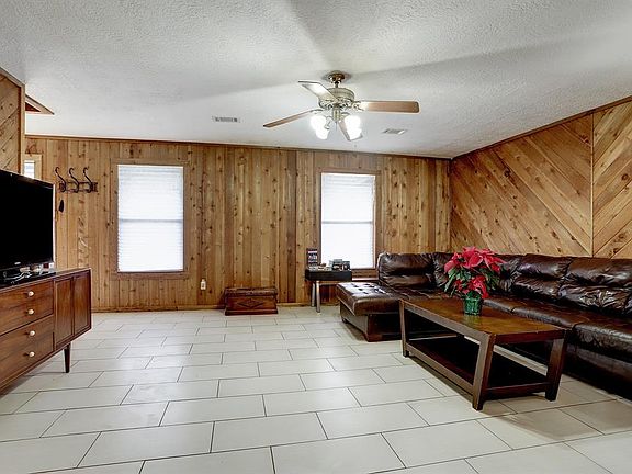 The double windows of the Family Room look out onto the front porch. There is a lighted ceiling fan.