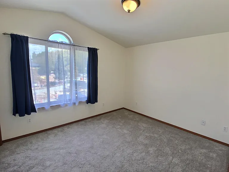 3rd Floor _ Primary bedroom with a vaulted ceiling, large arched window, and abundant natural light.