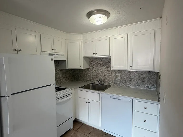 kitchen has white cabinets, fridge, dishwasher and electric stove