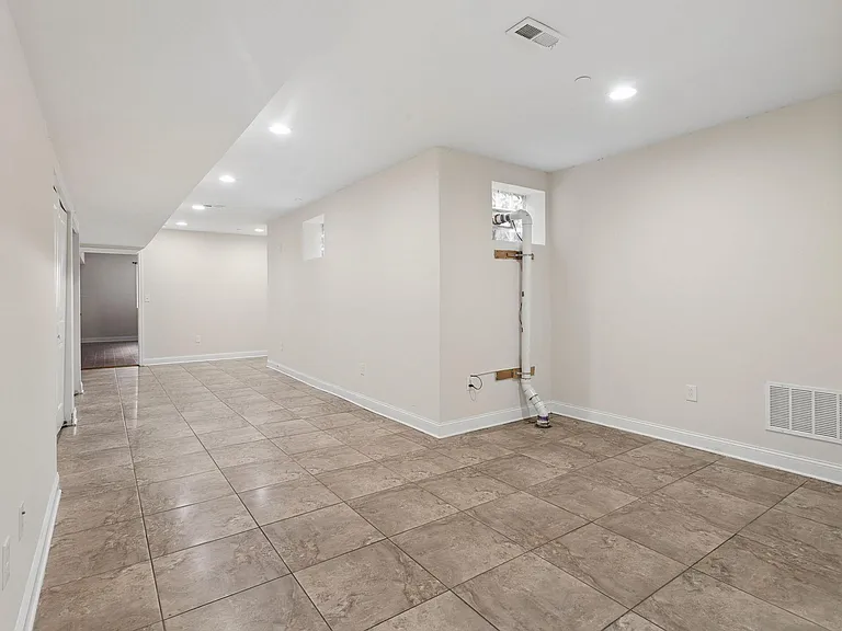 Open tiled lower-level flex space with recessed lighting and neutral wallsideal for storage, fitness, or a rec area.