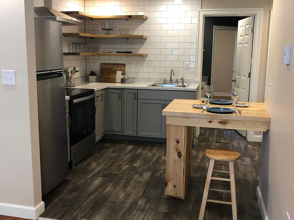 Kitchen with built-in butcher block eating area, white subway tile backsplash, new stainless steel appliances, and custom open shelving for lot of spaces for dinnerware and glassware.