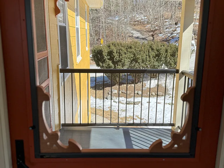 The balcony from the inside of the porch. There are also two plant hangers to hang hanging flowers or seasonal decorative hanging options.