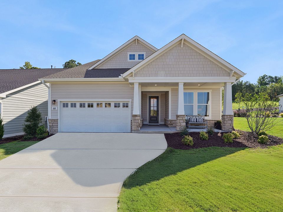 A well-maintained single-story house with a garage, surrounded by a neatly landscaped yard and a cle