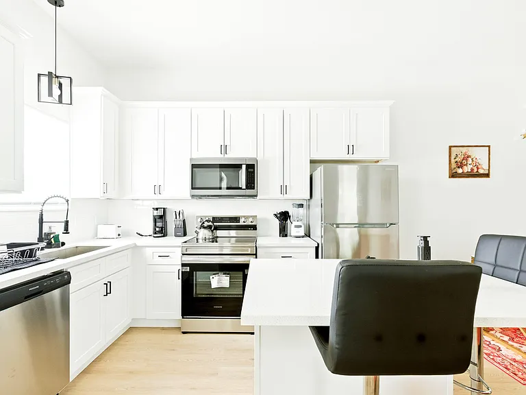 Eat-in kitchen with white shaker cabinets, quartz-style counters, and a center island plus stainless steel appliances.