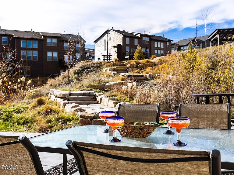 Side patio off kitchen faces hill to community playground and fire pit.