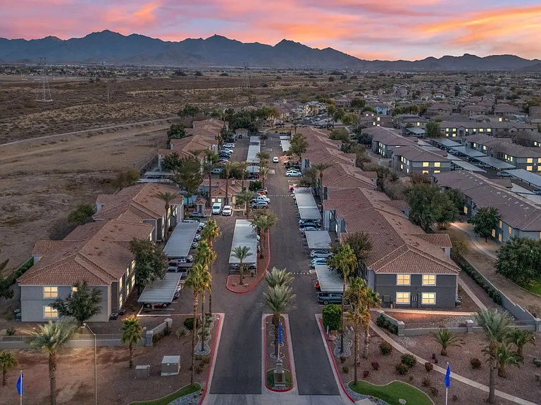 Aerial view of Sedona Peaks apartment community at twilight, showcasing desert landscape, mountain views, and well-lit residential buildings.