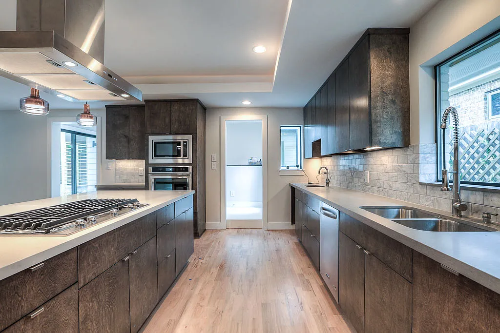 Working kitchen view _ long quartz counter run with double sink, bar sink, dishwasher, microwave/wall oven tower, and pass-through to the laundry/utility space - 4127 Underwood St