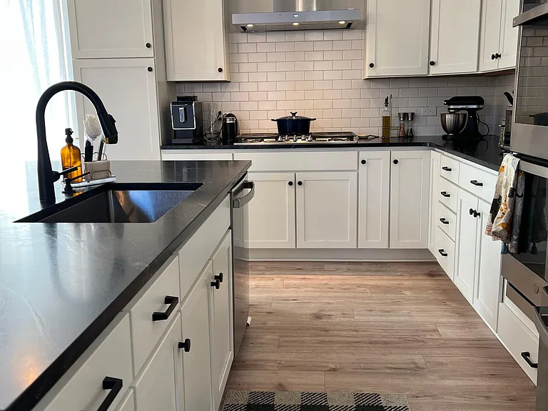 Vent goes to outside and does not circulate air inside. Deep kitchen sink with goose neck faucets. Matte black hardware. Shaker style cabinets.