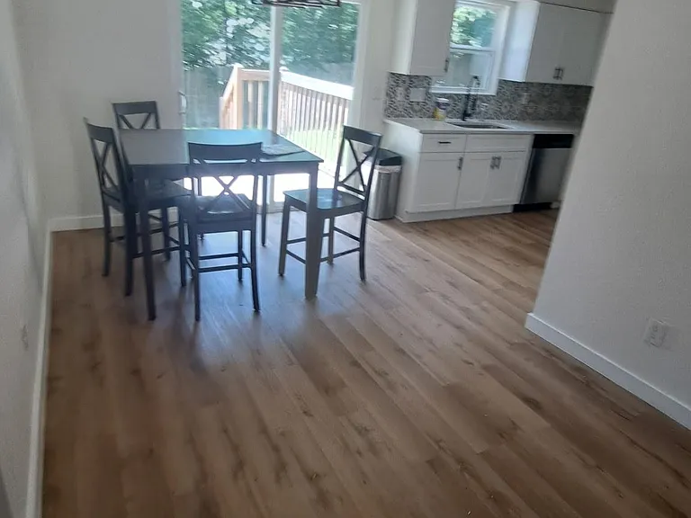 Open dining area flows into the kitchen and opens to a deck through sliding glass doors, offering easy indoor-outdoor living.