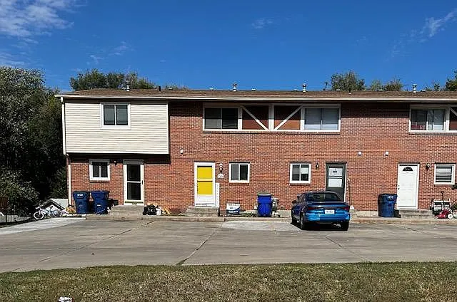 Front Facade. Second townhouse unit with the yellow door. Two parking spaces directly in front of unit and one along the street side of the parking lot.