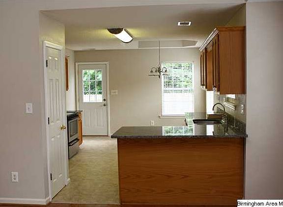 Kitchen has a breakfast bar with granite countertops and tile backsplash