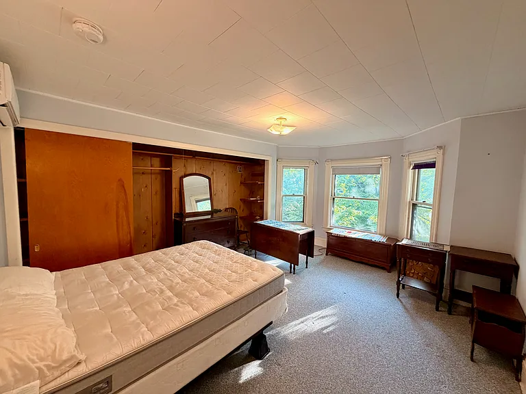 Upstairs front bedroom, showing heat pump (at left), closets, bay windows.