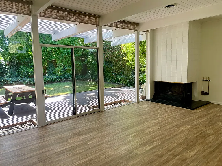 Photo taken from the living room towards the back yard, includes new hardwood flooring and the outside deck