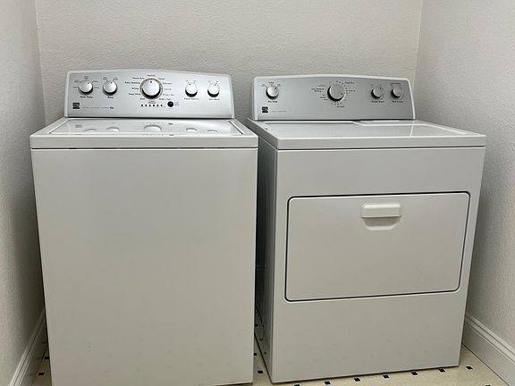 Full size washing machine and dryer in laundry room located in room at the end of the kitchen.