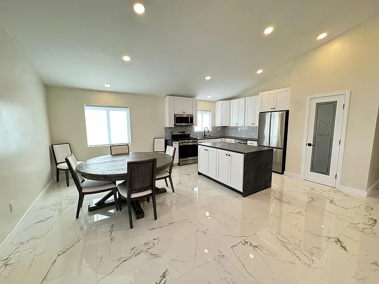 Open concept kitchen, dining and living room with vaulted ceilings and ample light.