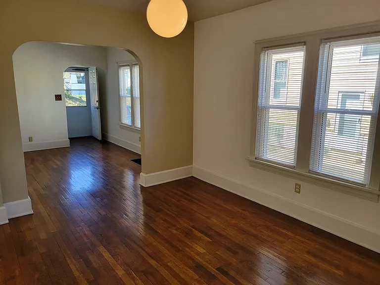 Dining room leading to Livingroom, front door to apartment and front carpeted porch.