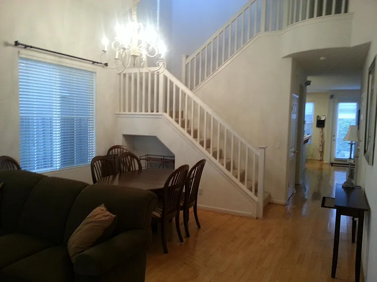 Entry from front door features high ceilings and beautiful oak hardwood floors. The hallway leads past a left-side powder room, coat closet, and right-side garage door, straight into the family room where a back door opens to the yard.