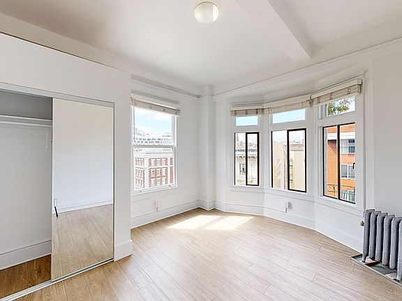 Bright bedroom with wood-like floor and a closet with mirror