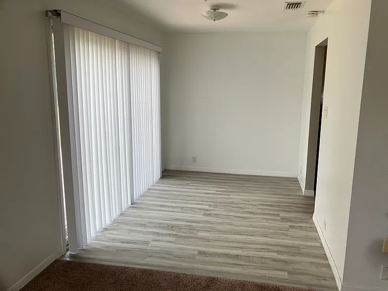 Dining room has sliding glass door to outside patio with pavers, and vinyl flooring that extends into the kitchen to the right