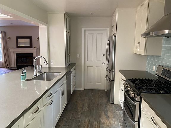 Custom designed high-end kitchen with soft-close drawers, quartz countertops, and so many drawers. Blue glass Ann Sacks tile on backsplash. Door leads to garage.