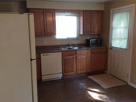 Kitchen with ceramic tile floor. Refrigerator, dishwasher and microwave included (as-is). Door to backyard.