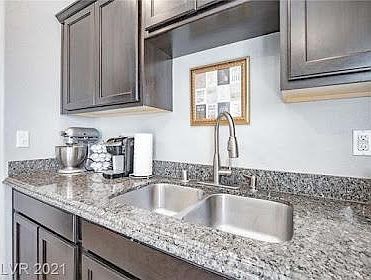 Kitchen with granite countertop and stainless steel double deep sink with dark wood cabinetry .