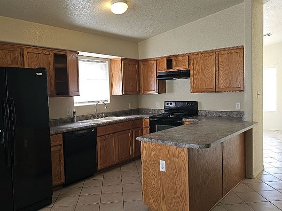 Kitchen includes electric stove, dishwasher and refrigerator.