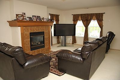 Beautiful living room is warmed by a tiled gas fireplace with a custom mantle.