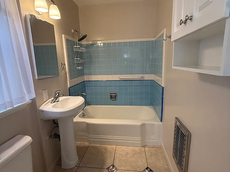 Bare bathroom with tub & shower, wall heater, & exhaust fan