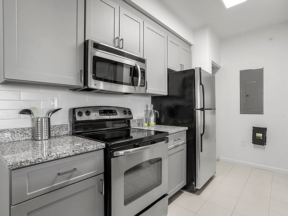 Renovated I Kitchen with grey cabinetry, tile backsplash, tile flooring, and stainless steel appliances