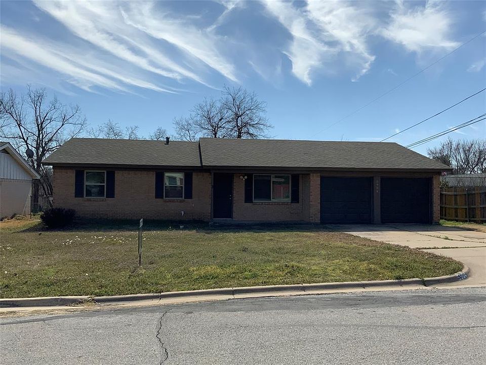 Ranch-style home featuring fence, a front lawn, concrete driveway, a garage, and brick siding