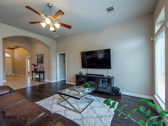 A view of the living room, arched entryway, and the front door from the breakfast area. Gorgeous wood-like floors grace this living room.