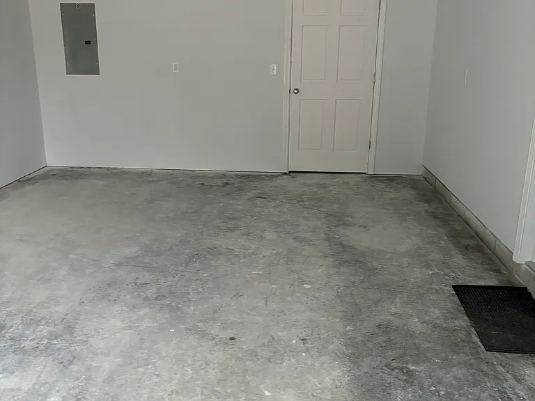 garage with utility panel and storage area to the rear of the garage bay, entry into the kitchen on the right