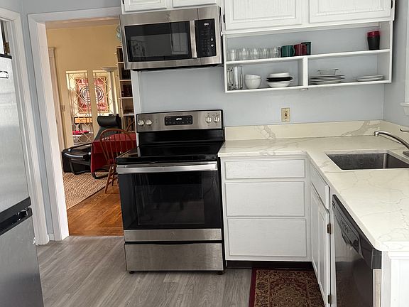 Kitchen from rear entrance. Stove, refrigerator, microwave, dishwasher.