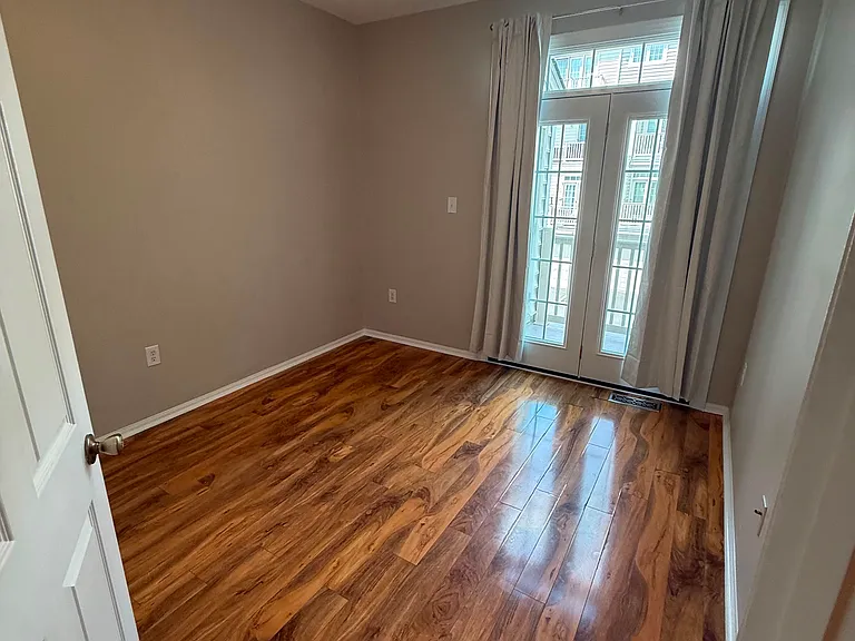 A light-filled third bedroom with rich wood flooring, high ceilings, and French doors providing access to the private balcony. A comfortable and flexible space to suit your lifestyle.