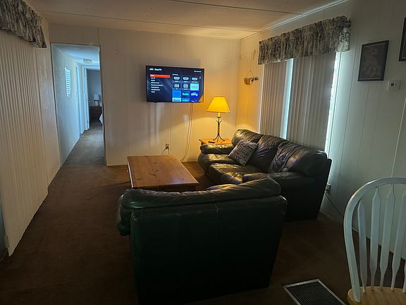 Spacious living room with couch, arm chair and 49 inch Roku television.