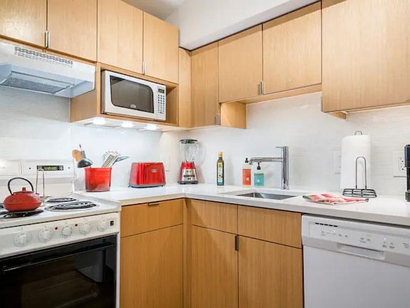 The kitchen counter is quartz, and there is plenty of kitchen storage in the custom cabinetry. The kitchen includes a refrigerator/freezer, dishwasher, oven/stove w/ a hood, and a microwave.